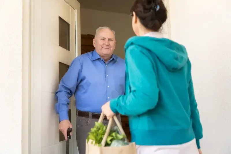 Caregiver bringing food to an older adult