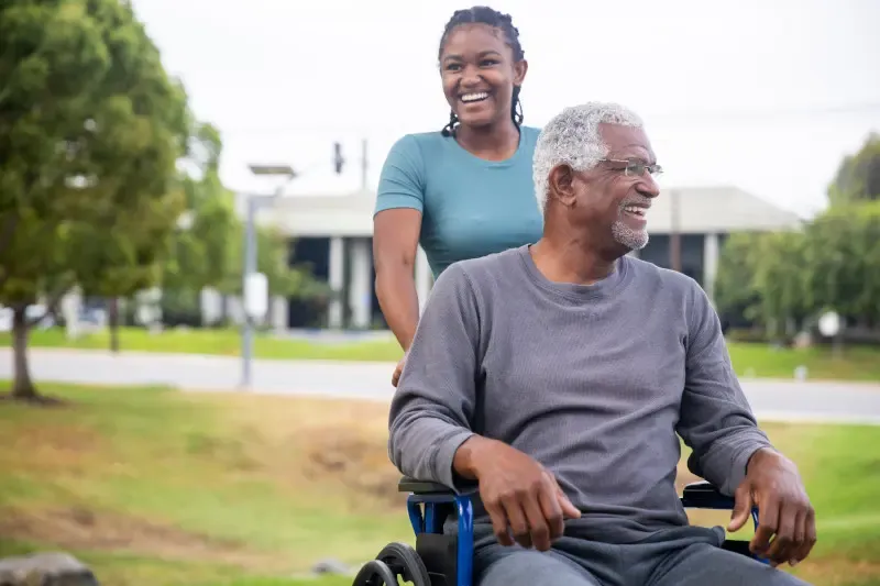 Young woman pushing older adult in wheelchair