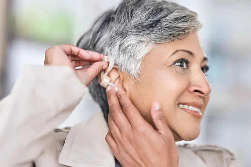 Mature woman putting on hearing aid
