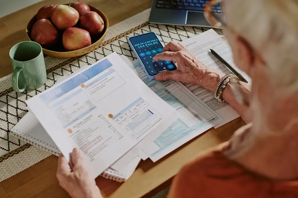 Mature adult looking at bills and using a calculator